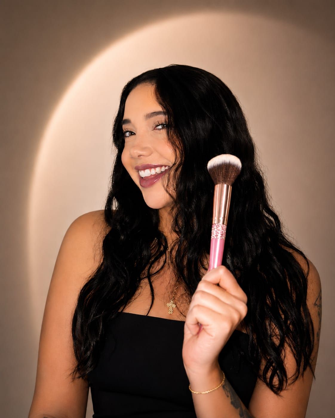 Sara, maquilladora de Glowy with Sara, sonriendo con una brocha rosada en la mano